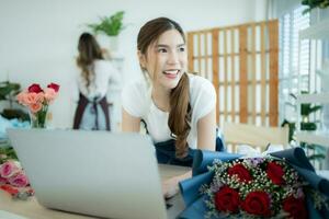 jong Aziatisch vrouw bloemist werken met laptop in bloem winkel foto