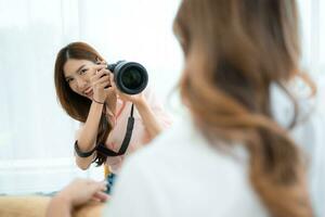 mooi Aziatisch vrouw fotograaf nemen afbeelding met professioneel camera Bij huis foto
