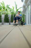 gelukkig senior vrouw in rolstoel gebruik makend van digitaal tablet Bij huis. foto