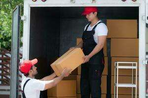 Aziatisch levering Mens in uniform leveren pakket naar klant in terug van vrachtwagen. foto
