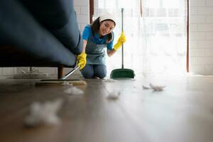 jong vrouw schoonmaak de verdieping met een bezem in de leven kamer. foto