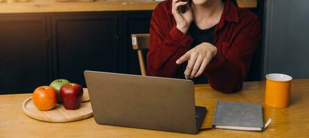 vrouw studenten Notitie van de boeken Bij de Aziatisch meisje bibliotheek zittend Bij sofa gebruik makend van laptop computer en tablet naar zoeken een online informatie. in leven kamer foto