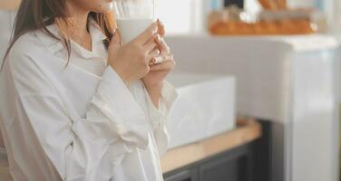 portret van een tevreden jong Aziatisch vrouw drinken melk van de glas geïsoleerd over- wit achtergrond foto