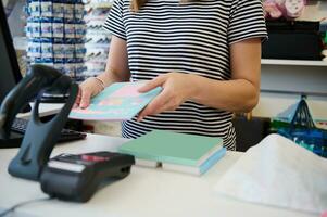 detailopname verkoop vrouw hand- scannen schrijfboeken gebruik makend van streepjescode scanner, staand door teller in de school- schrijfbehoeften op te slaan foto