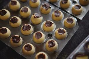 detailopname van fabricage chocola truffels. bolvormig mallen van wit chocola vol van donker chocola vulling . foto