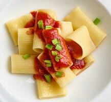 vlak leggen. detailopname van een gezond veganistisch maaltijd van een traditioneel gekookt Italiaans pasta met tomaat saus en groen ui garneren. gezond aan het eten concept foto