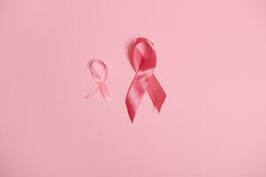 satijn roze linten bewustzijn, Internationale symbool van borst kanker bewustzijn maand in oktober, geïsoleerd roze achtergrond, kopiëren ruimte. oktober roze dag, wereld kanker dag, nationaal kanker overlevende zeggen. foto