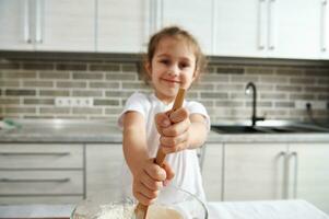 zacht focus Aan wazig mooi glimlachen meisje handen Holding houten lepel en kneden deeg. kinderen Koken foto