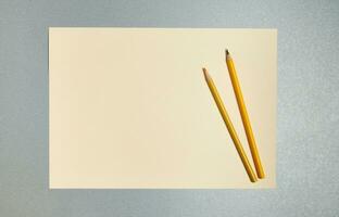 vlak leggen. houten potloden Aan een vel van geel papier. top visie Aan een grijs achtergrond foto