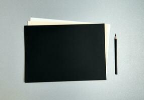 zwart potlood De volgende naar ontwerper papier van verschillend kleuren Aan een grijs achtergrond. vlak leggen. top visie foto