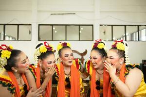 een groep van traditioneel Javaans dansers lachend samen met belachelijk gezichten en vol van vreugde terwijl Aan stadium foto