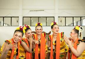 een groep van traditioneel Javaans dansers lachend samen met belachelijk gezichten en vol van vreugde terwijl Aan stadium foto