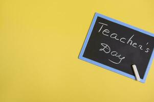 vlak leggen van een schoolbord met opschrift leraren dag Aan een geel achtergrond met kopiëren ruimte voor tekst foto
