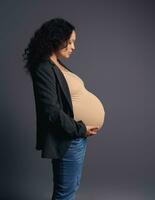 mooi multi-etnisch zwanger vrouw Holding haar buik in zwangerschap 36 week, gevoel gelukkig emoties ervan uitgaand haar baby foto