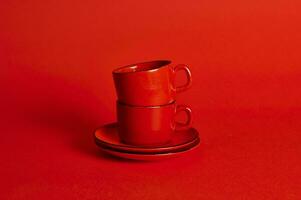 twee rood keramiek cups en schoteltjes Aan rood achtergrond met zacht schaduw, kopiëren ruimte. foto