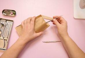 hoog hoek visie van een podoloog handen opening een zak met steriel roestvrij staal instrumenten voor een professioneel pedicure foto