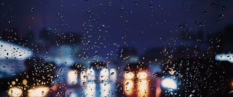 het rijden in regenen. regen Aan auto voorruit of auto venster in regenachtig seizoen en wazig verkeer weg in achtergrond. regen druppels Aan auto spiegel. weg in regen. motregen regenen neemt af het rijden zichtbaarheid. foto