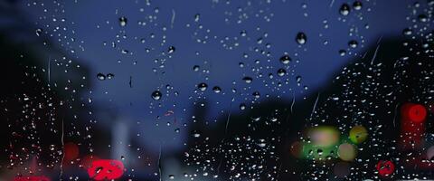 het rijden in regenen. regen Aan auto voorruit of auto venster in regenachtig seizoen en wazig verkeer weg in achtergrond. regen druppels Aan auto spiegel. weg in regen. motregen regenen neemt af het rijden zichtbaarheid. foto