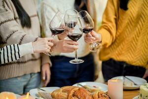 vrolijk vrienden genieten van huis verjaardag vakantie feest. Aziatisch vrienden juichen drinken rood wijn vieren Kerstmis of nieuw jaar partij foto