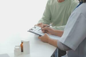 een Gezondheid bezoeker met tablet uitleggen een senior vrouw hoe naar nemen pillen. foto