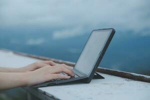 jong bedrijf vrouw werken Bij de computer in cafe Aan de steen. jong meisje terugschakelen werken Bij een laptop Bij zonsondergang of zonsopkomst Aan de top van de berg naar de zee, werken dag. foto