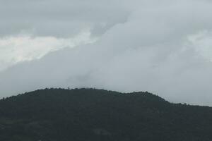 mooi panoramisch visie van mist en wolken in ver weg lagen bergen reeks met blauw lucht in ochtend- foto