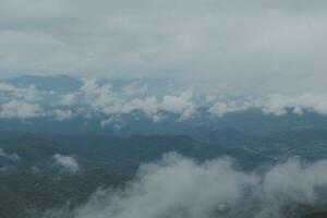 mooi panoramisch visie van mist en wolken in ver weg lagen bergen reeks met blauw lucht in ochtend- foto