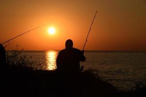 silhouet van een man die aan het vissen is foto