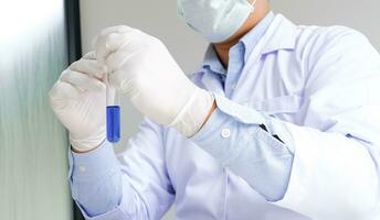 wetenschap vernieuwend mannetje medisch of wetenschappelijk laboratorium onderzoeker presteert tests met blauw vloeistof in laboratorium. uitrusting wetenschap experimenten technologie coronavirus covid-19 vaccin Onderzoek foto