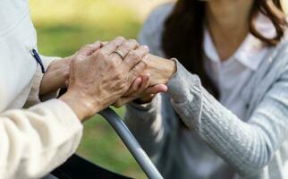 familie verhouding Aziatisch senior vrouw in rolstoel met gelukkig dochter Holding verzorger voor een hand- terwijl uitgeven tijd samen foto