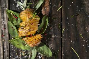 een stapel van aardappelen met kruiden en specerijen Aan een houten tafel foto