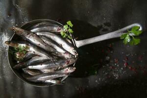 vers sardines in een zwart schotel met kruiden foto