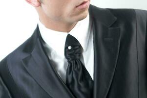 een Mens in een zwart pak en stropdas op zoek naar beneden foto