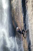 een persoon Aan een touw beklimming omhoog een waterval foto