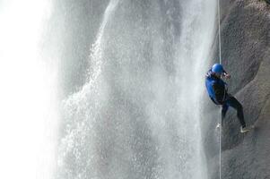 een persoon Aan een touw beklimming omhoog een waterval foto