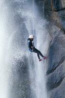 een persoon Aan een touw beklimming omhoog een waterval foto