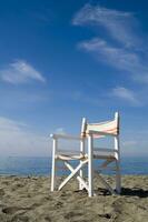 een strand stoel Aan de zand met een blauw lucht foto