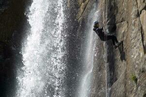 een persoon Aan een touw beklimming omhoog een waterval foto