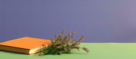 een oranje boek of notitieboekje met lavendel bloemen binnen is uitgelicht Aan een groen achtergrond met foto