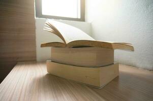 Open oud boeken Aan een houten tafel met venster licht foto