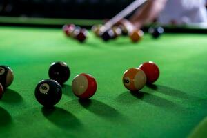 man's hand- en keu arm spelen snooker spel of voorbereidingen treffen het richten naar schieten zwembad ballen Aan een groen biljart tafel. kleurrijk snooker ballen Aan groen fries. foto