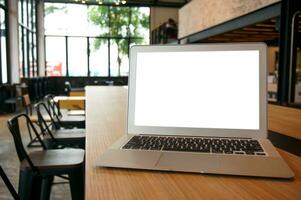 laptop met bespotten omhoog blanco scherm Aan houten tafel in voorkant van cafe ruimte voor tekst. Product Scherm computer laptop montage- technologie freelance werk concept foto