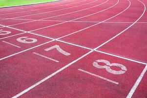 getallen beginnend punt Aan rood rennen volgen, rennen bijhouden en groen gras, direkt atletiek rennen bijhouden Bij sport stadion foto
