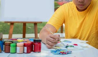 aan het leren de kunst van tekening en schilderij buiten de klas door beoefenen menging poster kleuren van junior hoog school- studenten Aan de tafel. foto