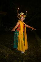 een traditioneel Javaans danser dansen met kleurrijk bloemen Aan haar vuist terwijl Aan stadium foto