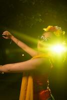 een mooi Sundanees danser poses en dansen in een glamoureus jurk en sjaal in voorkant van de stadium licht foto