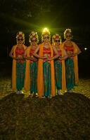 een groep van Indonesisch traditioneel dansers dans met hun vrienden in voorkant van de stadium lichten foto