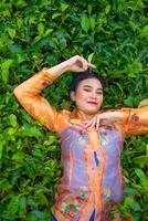 een Indonesisch vrouw is aan het liegen Aan een groen thee tuin terwijl Aan vakantie foto