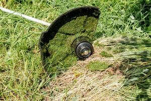 een deel van een elektrisch gazon maaier in de gras, detailopname foto