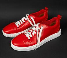 nieuw rood leer sportschoenen met wit zolen Aan een zwart achtergrond foto